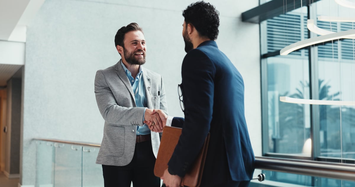 Collaboration, handshake and meeting with business people at window in office for partnership.